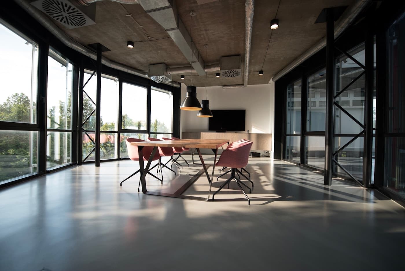 Sala de reuniones luminosa, con una mesa de madera y grandes ventanales